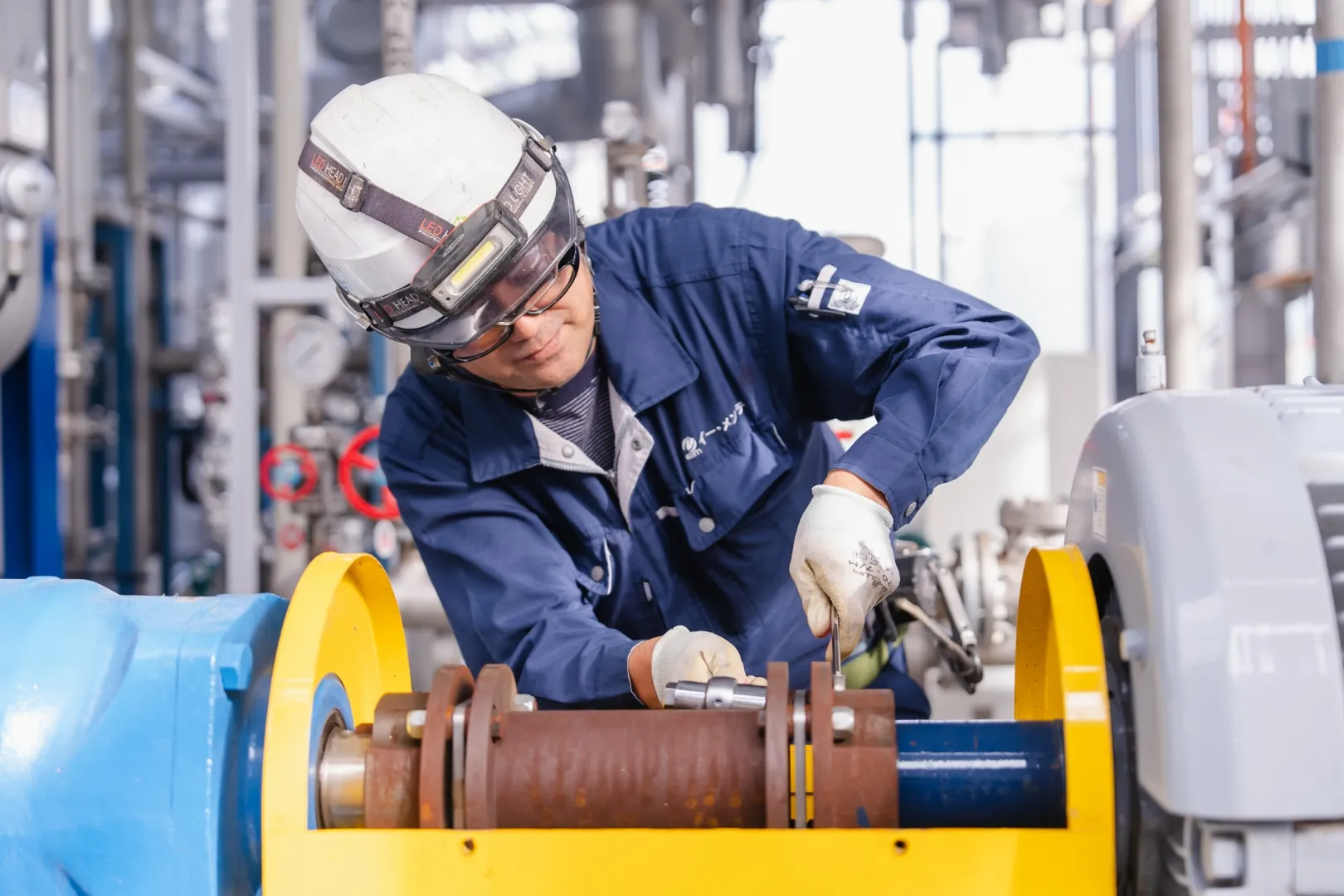 プラント設備で機械部品の調整作業を行う作業員の様子