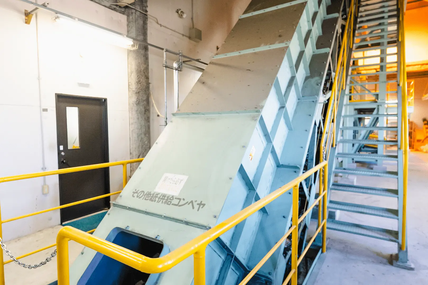 廃棄物搬送用の傾斜コンベアが室内に設置されている様子