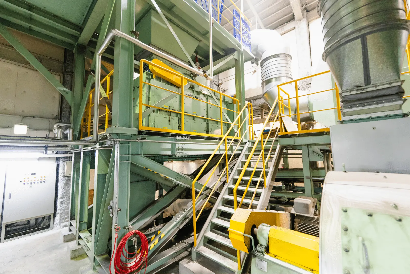 多層構造の大型産業機械と排気ダクトが設置された工場内の一角