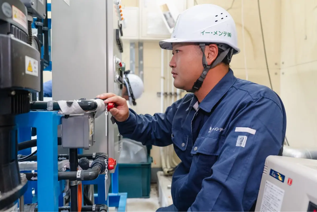 作業員が屋内で配管設備のバルブを操作している様子